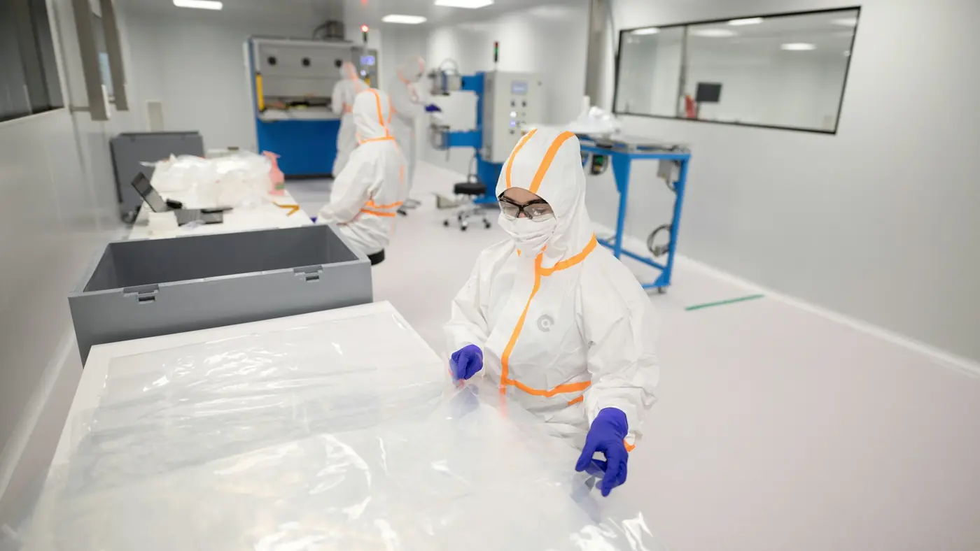 Workers in protective suits inside a cleanroom